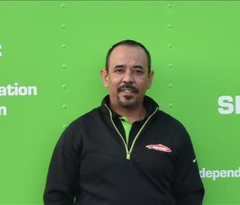 Image of male employee with black shirt in front of green wall